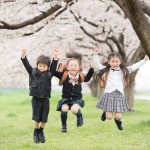 入学式でジャンプして喜ぶ3人の小学生