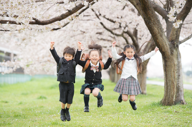 入学式でジャンプして喜ぶ3人の小学生