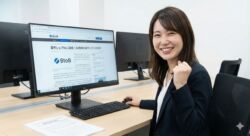 自社のプレスリリースがWebメディアに掲載された記事を見て、デスクで笑顔でガッツポーズをするBtoB広報担当者