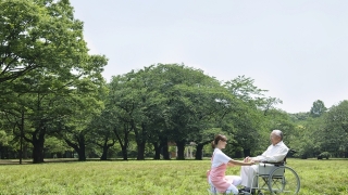 公園で車いすの患者さんと介護士さん