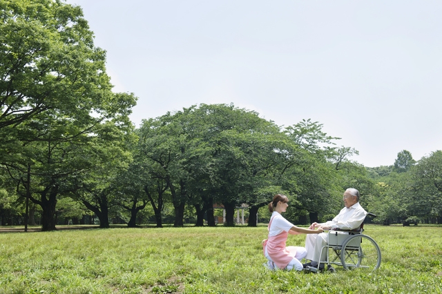 公園で車いすの患者さんと介護士さん