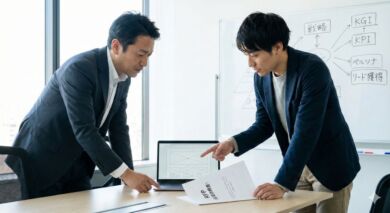 BtoBサイト制作の打ち合わせ風景。RFP（提案依頼書）とワイヤーフレームを見ながら戦略を議論する担当者とディレクター